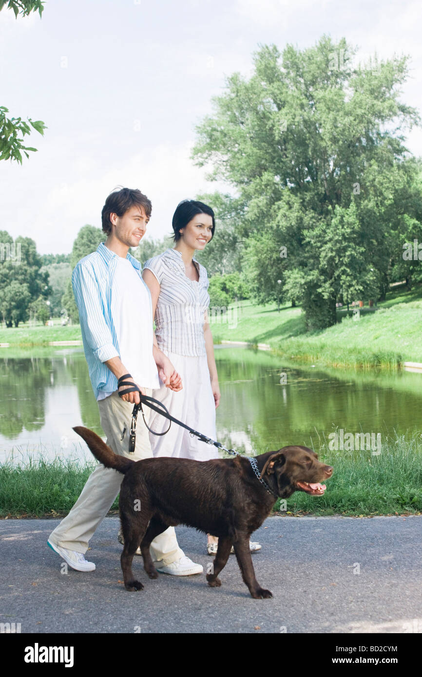 couple walking the dog in park Stock Photo - Alamy