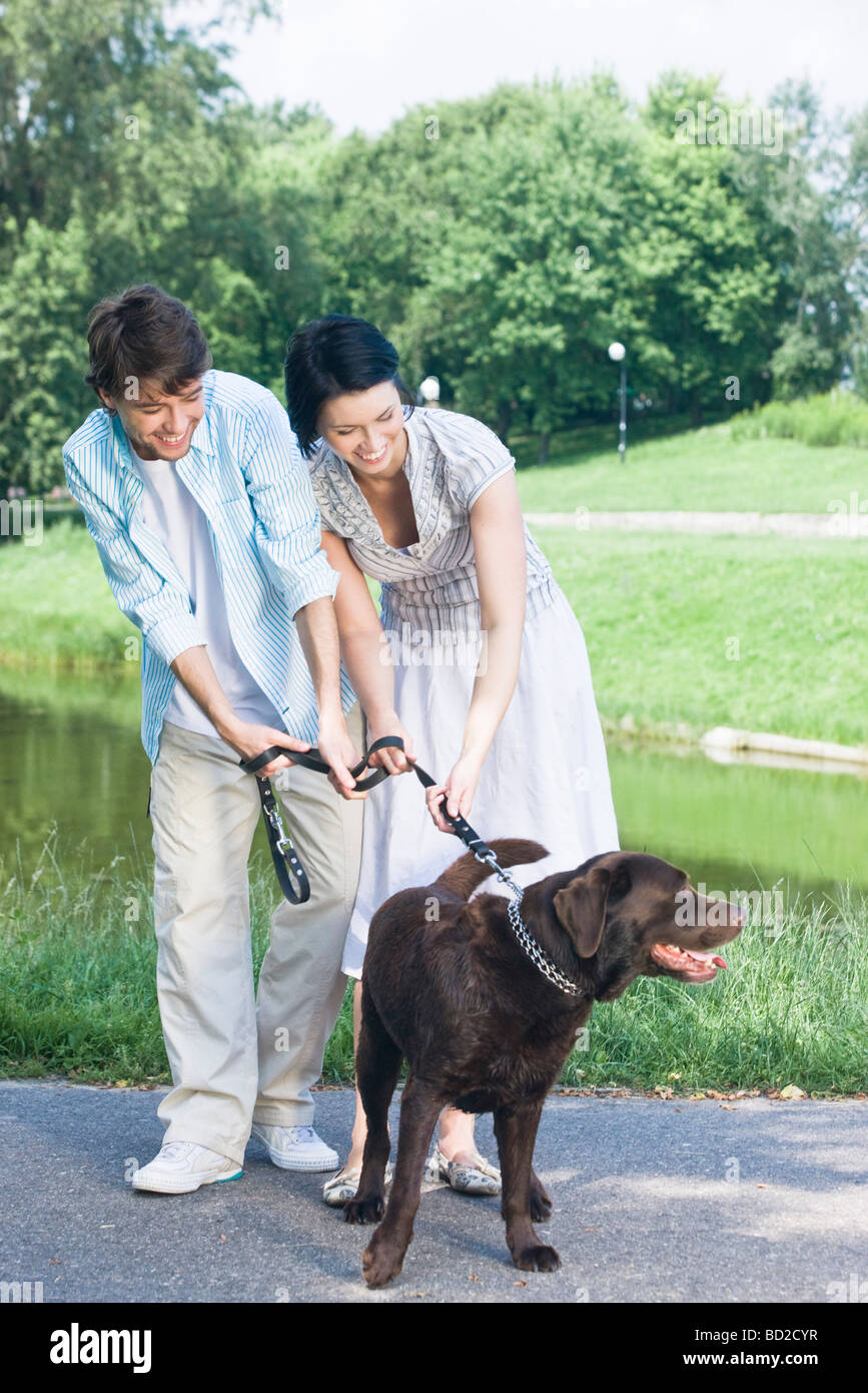 Couple walking with dog in park Stock Photo - Alamy