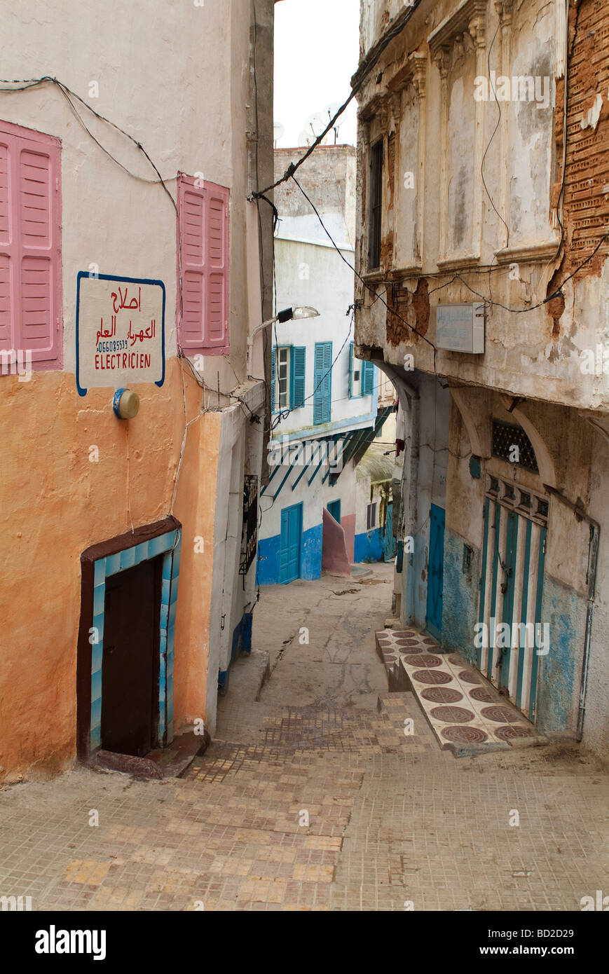 Narrow street sloping downward with the Electrician shop Larache Morocco Stock Photo