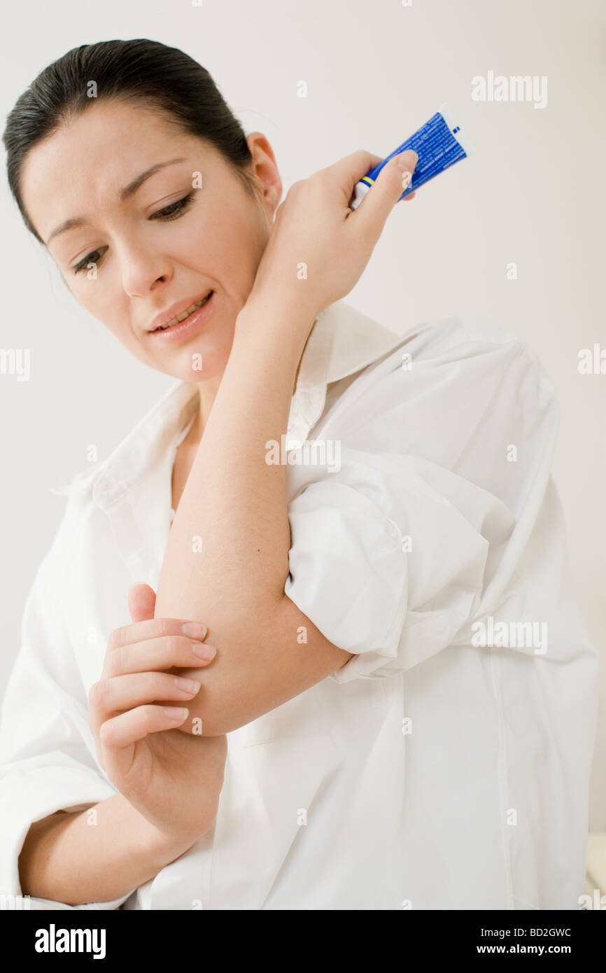Woman putting ointment on elbow Stock Photo