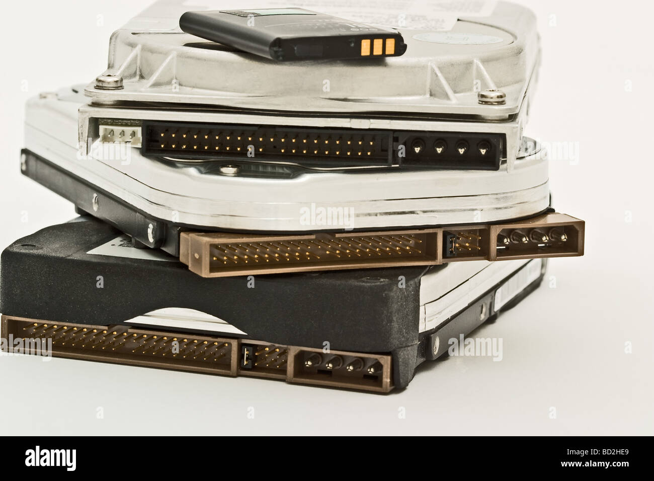 Pile of computer hard drives with a small battery on the top Stock Photo
