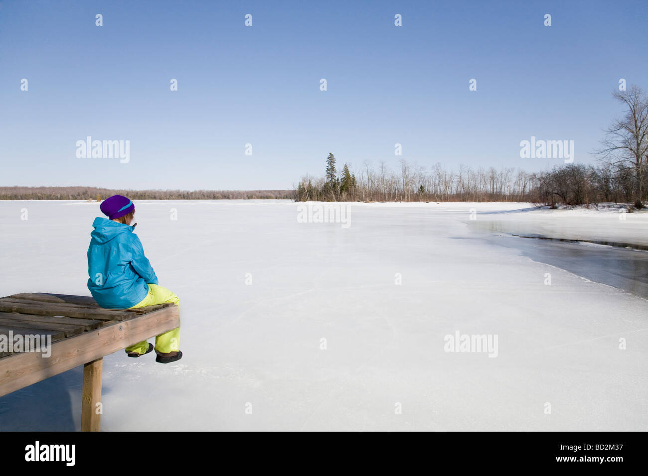 Woman Relaxing on Dock by Frozen Lake Stock Photo