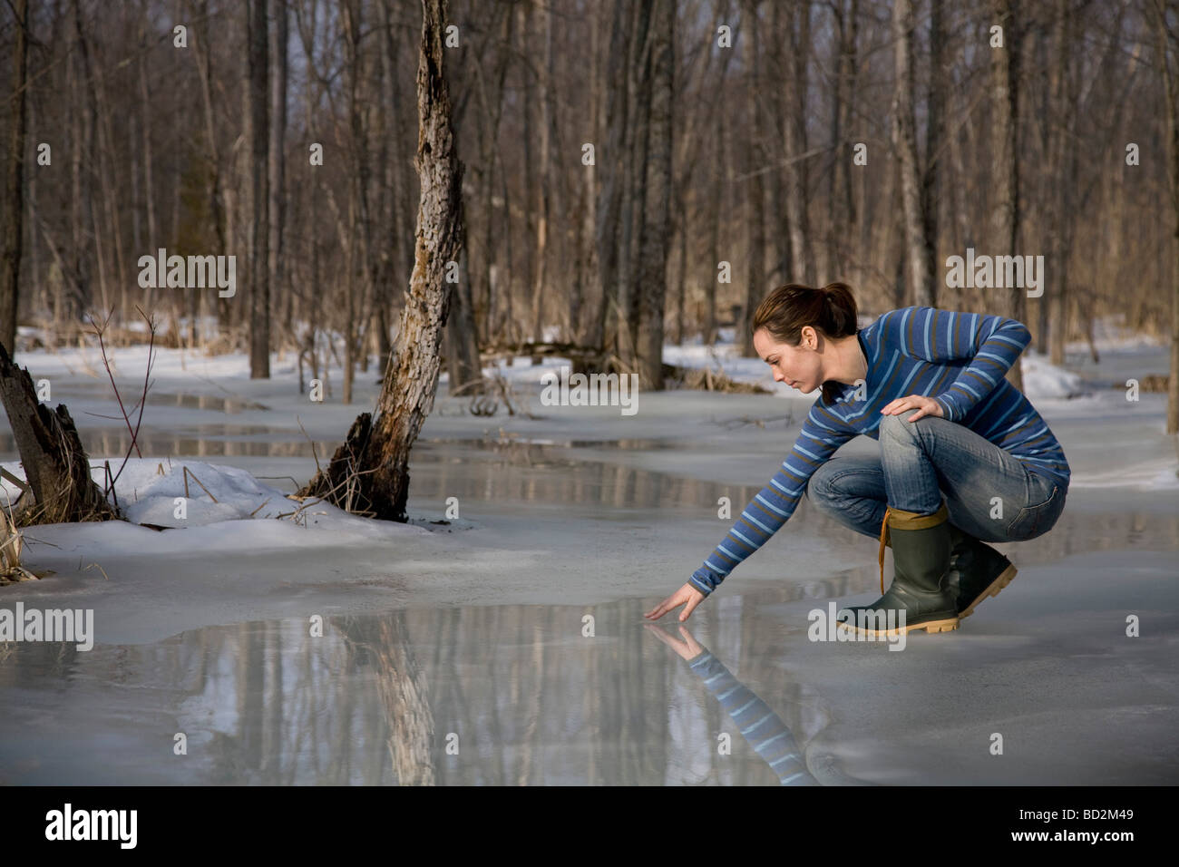 Woman Testing Melting Ice on Pond Stock Photo