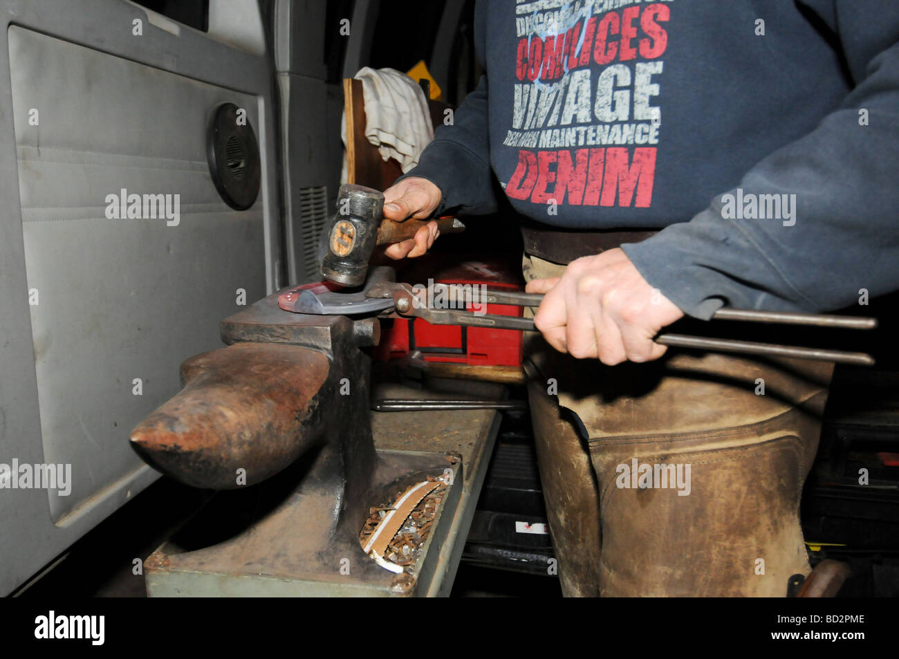 Farrier preparing a horseshoe in his mobile Shaping the heated