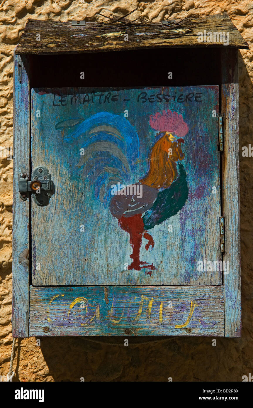 A painted wooden letter box featuring a colorful Cockerel outside a village house in Provence. South of France Stock Photo