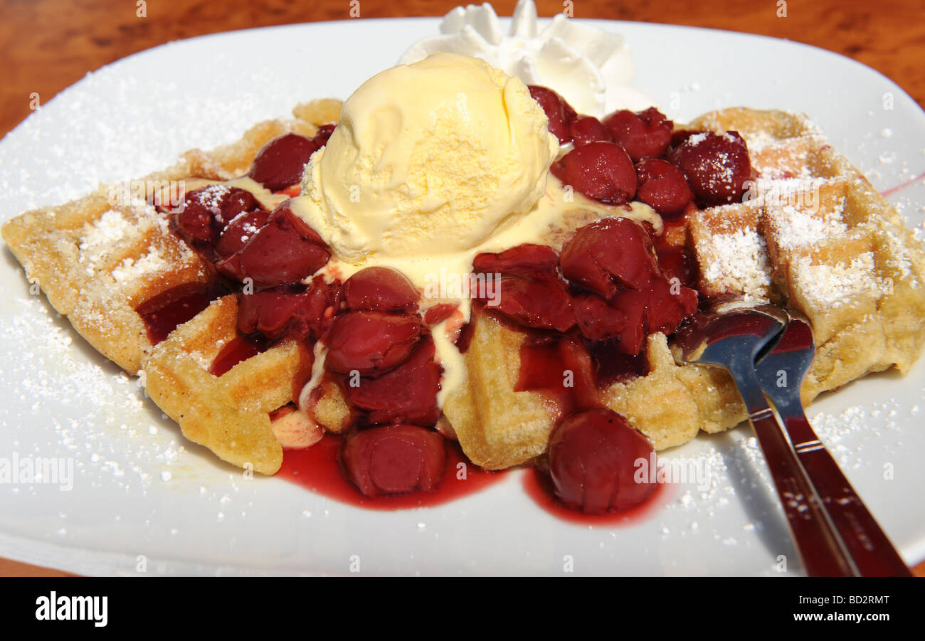 Fresh waffles with red cherries ice cream and whipped cream Focus on centre of image Stock Photo