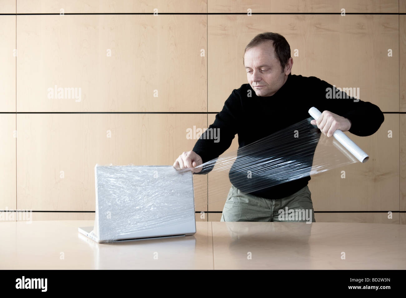 Man wrapping computer with plastic film Stock Photo Alamy