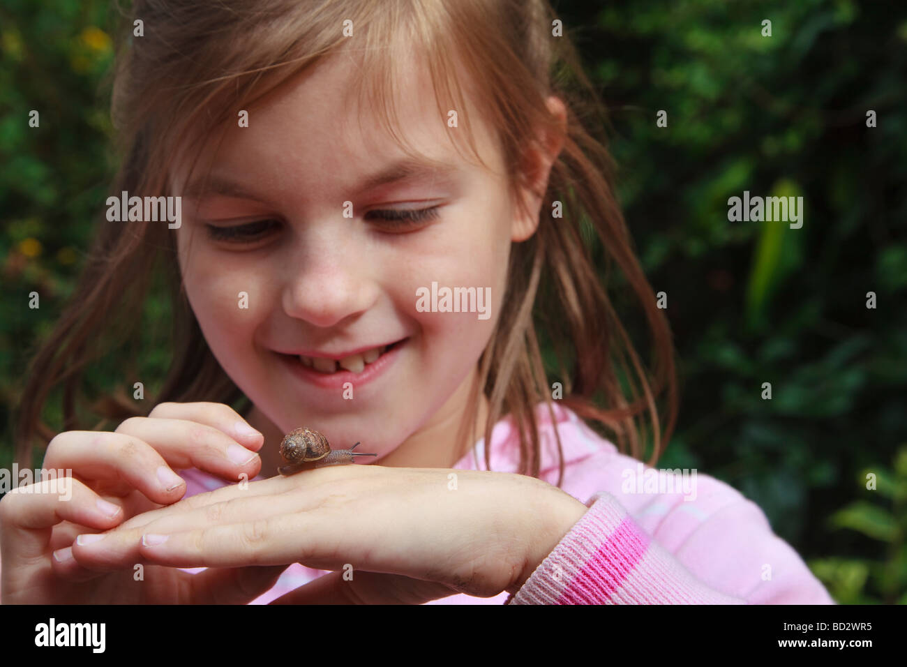 Young girl with snail crawling on her hand Stock Photo