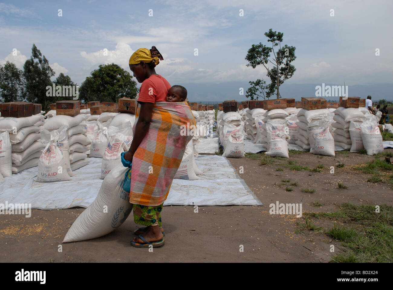 A displaced Congolese woman drags a heavy sack of corn soya blend donated by USAID at World Food Programme WFP distribution point in North Kivu, Congo Stock Photo