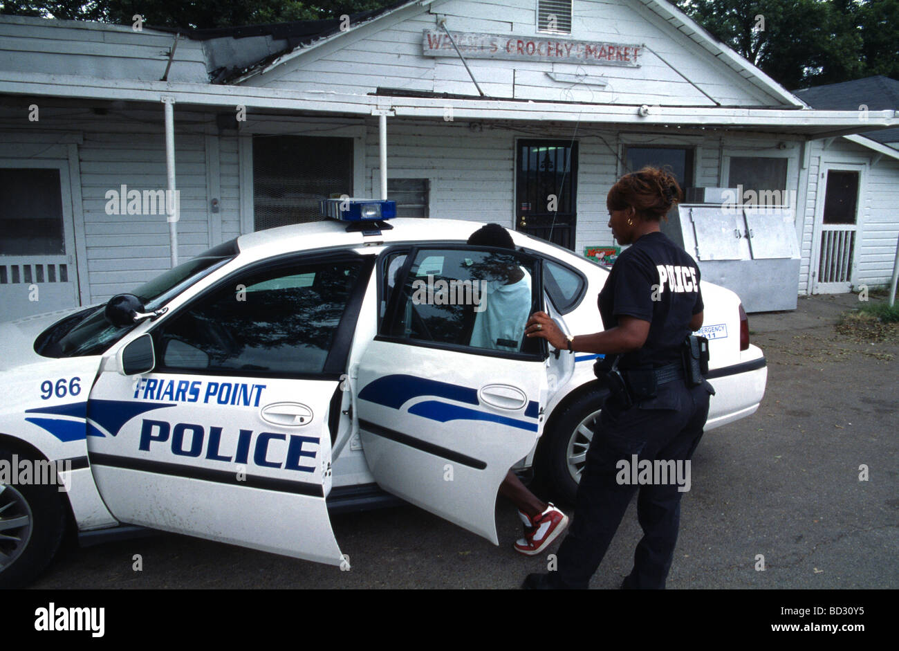 Black female police officer arresting a black teenager in Friars Point Mississippi USA Stock Photo