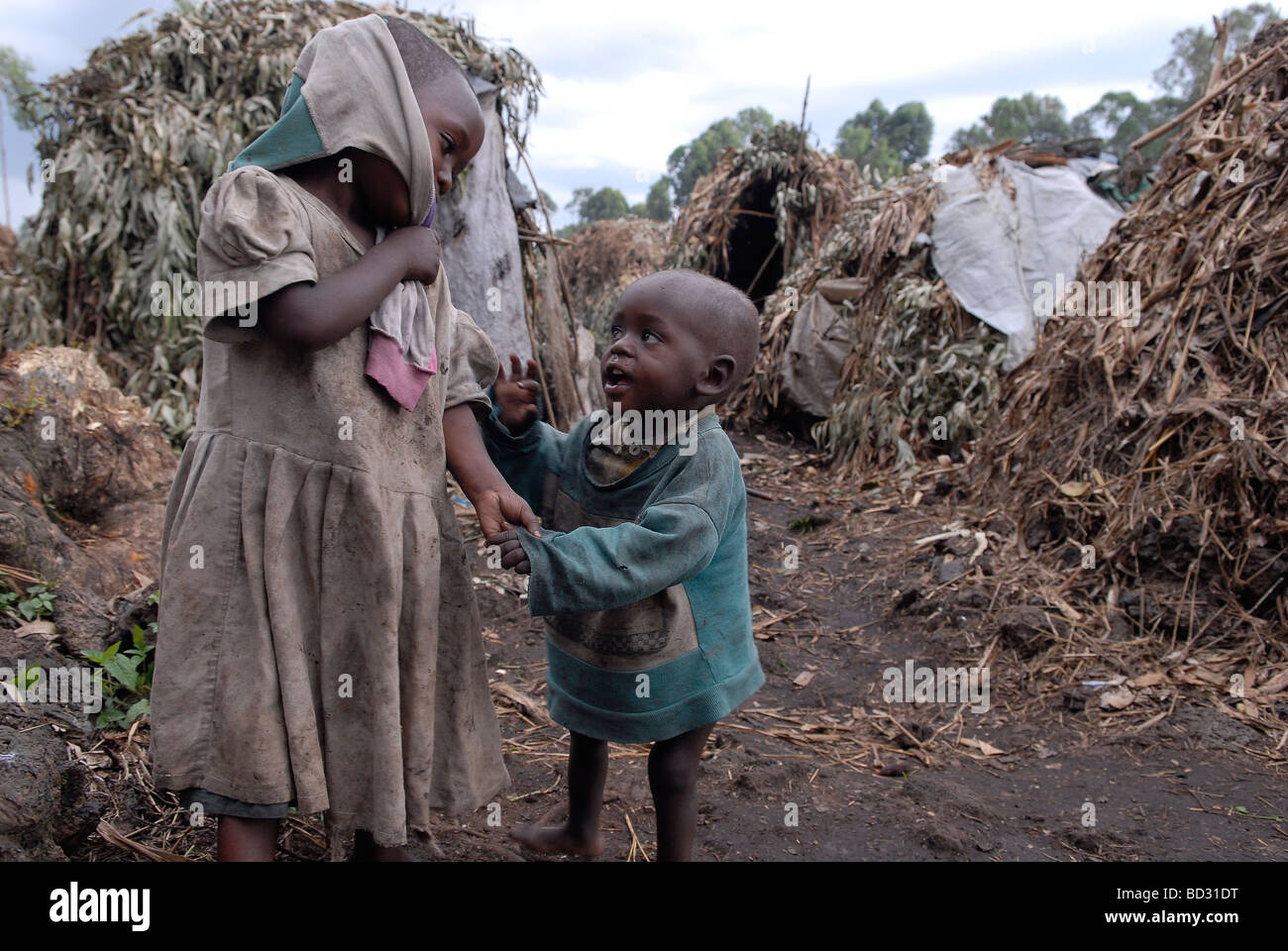 Young Congolese children stand amid makeshift straw huts in an IDP camp in North Kivu province DR Congo Africa Stock Photo