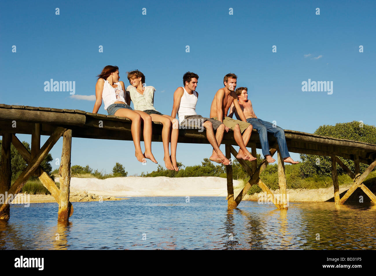 Group of young people sitting on jetty Stock Photo