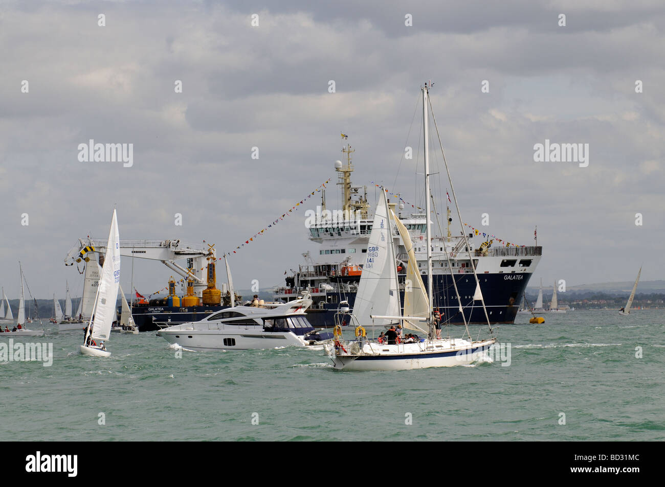 Sailing activity and spectators Cowes Regatta and the THV Galatea a Trinity House vessel anchored for cowes week  England Stock Photo