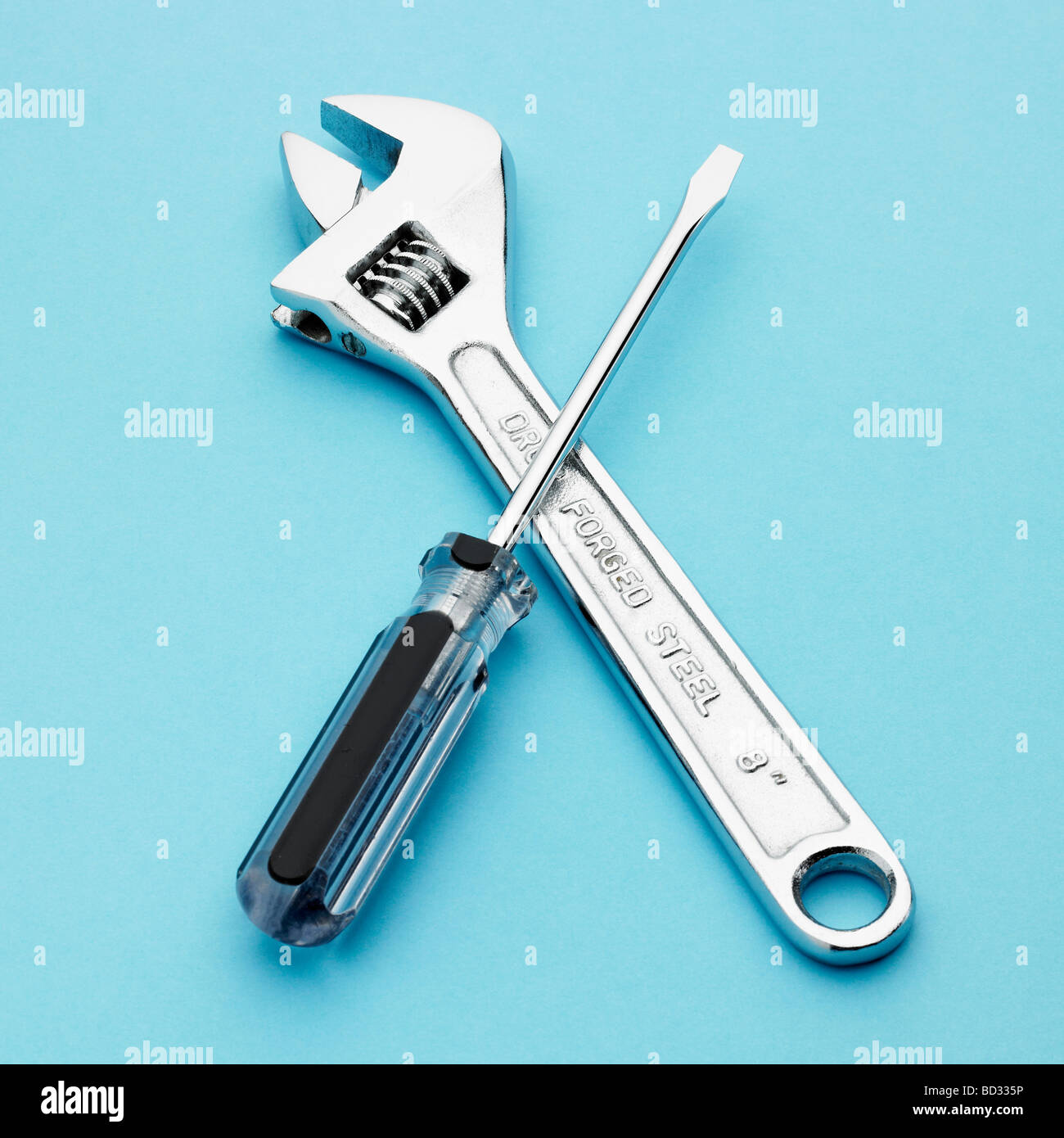 Adjustable spanner and screwdriver on blue background. Stock Photo