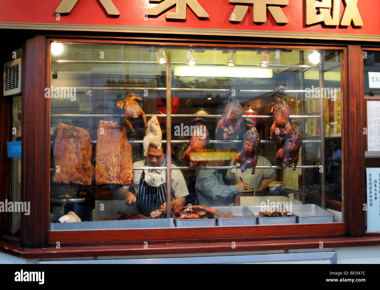 Chef working in the window of a Chinese restaurant in the Chinatown district of London Stock Photo