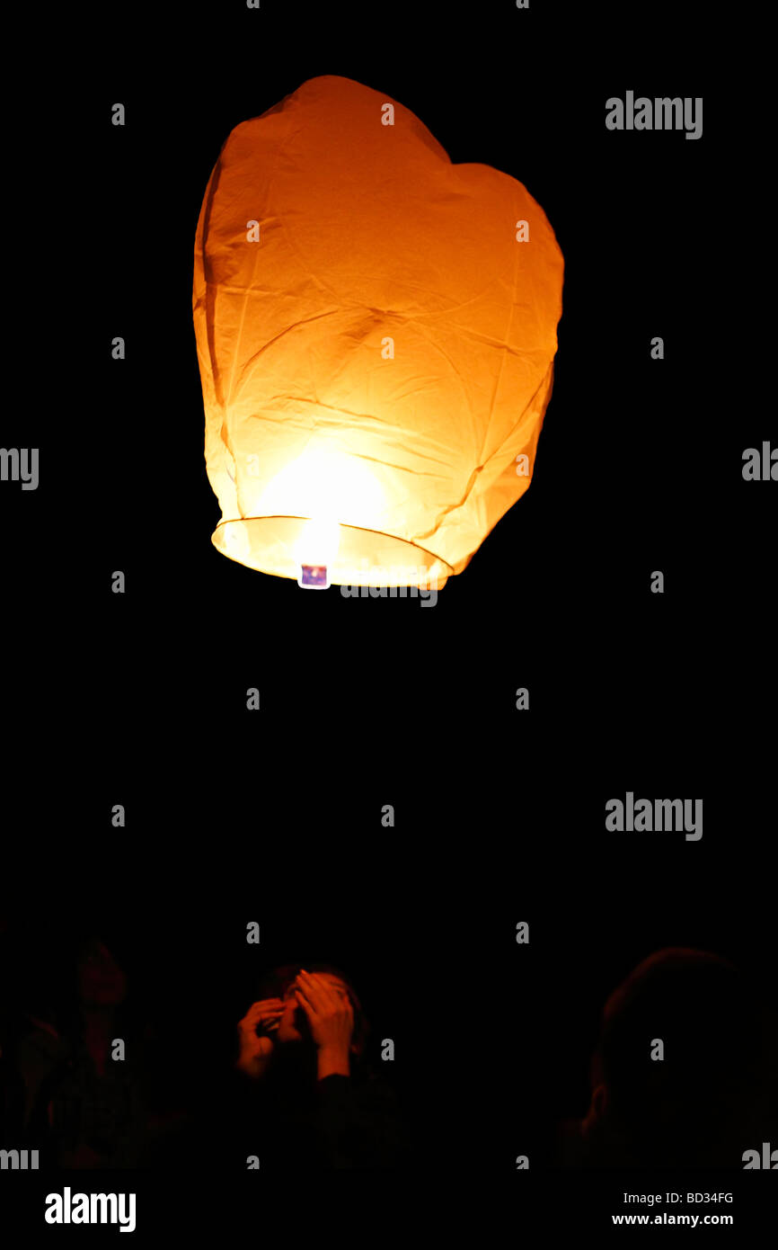 woman launches a sky lantern; floating lantern Stock Photo