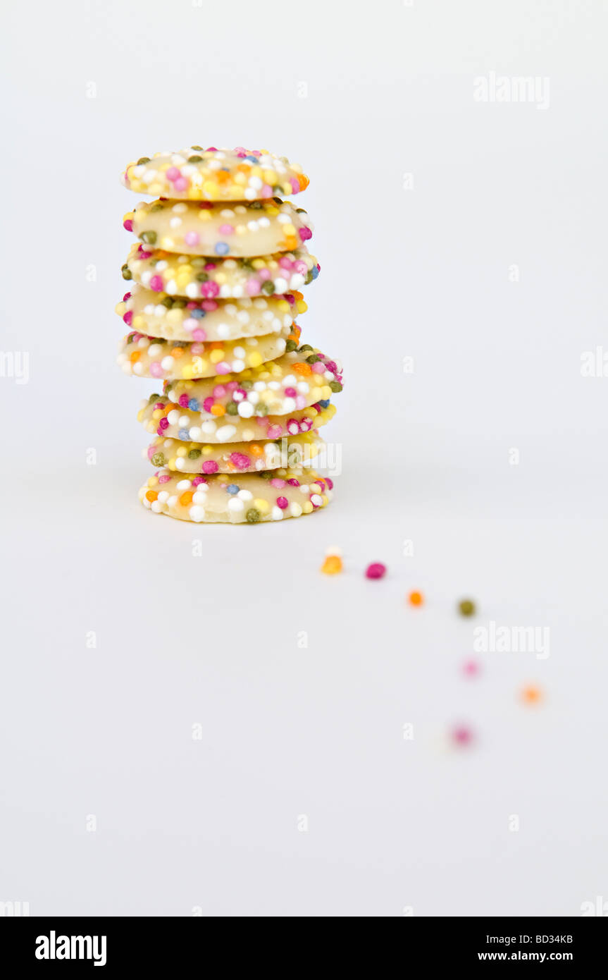 Still life artistic shot of white chocolate button sweets covered in sprinkles taken against a white background Stock Photo