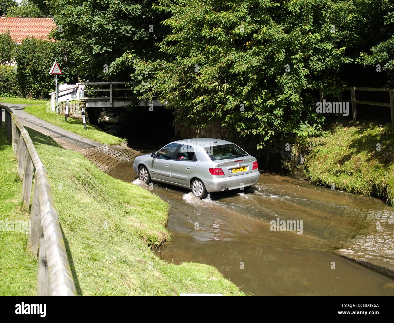 A motor car crossing a ford over a stream on a back road in a North Yorkshire village Stock Photo