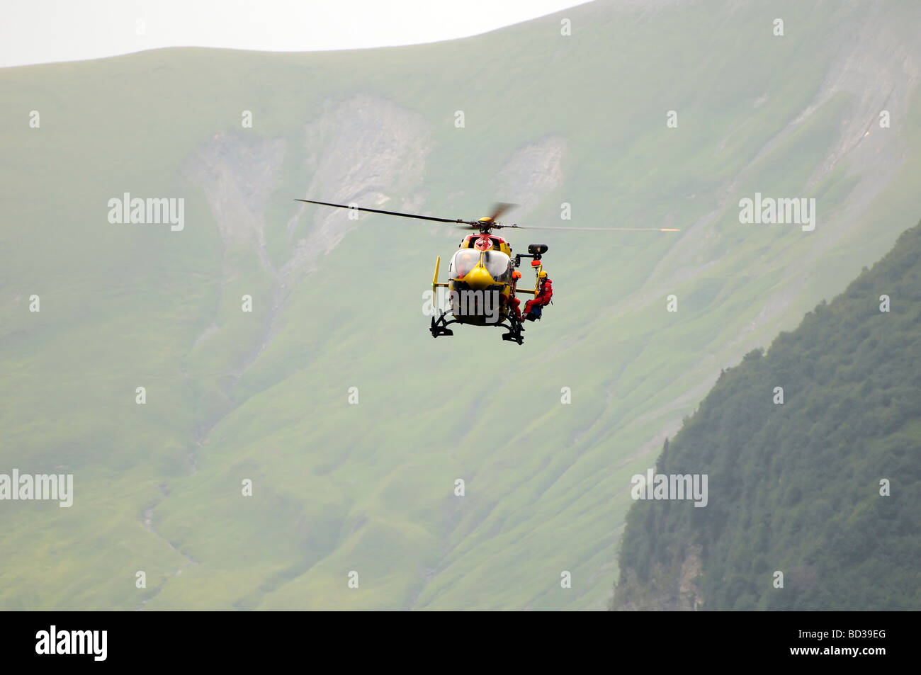 French mountain rescue helicopter, Eurocopter EC145.  Rescuing a Tour de France spectator who fell down a cliff in the Alps. Stock Photo