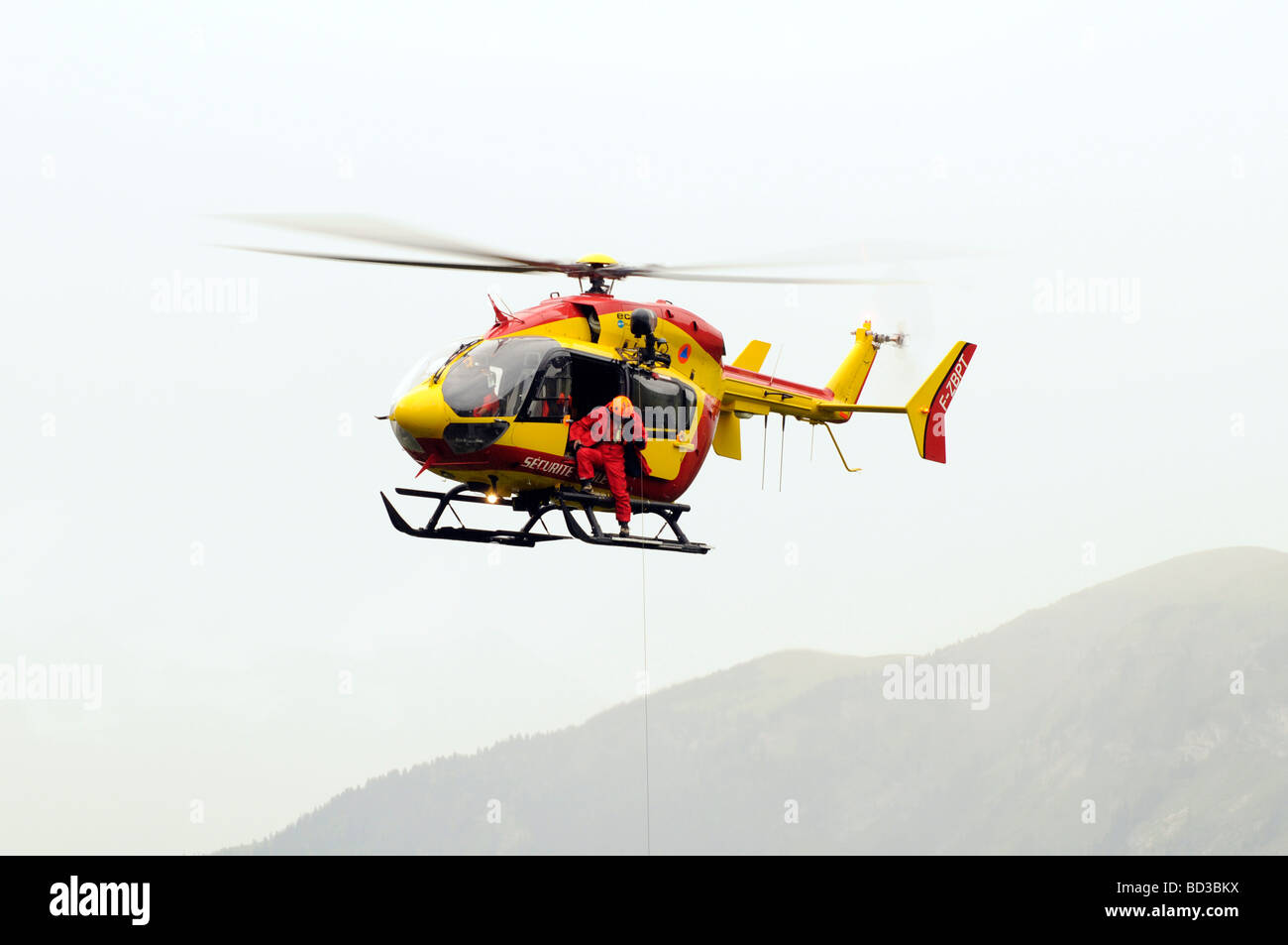 French mountain rescue helicopter, Eurocopter EC145.  Rescuing a Tour de France spectator who fell down a cliff in the Alps. Stock Photo