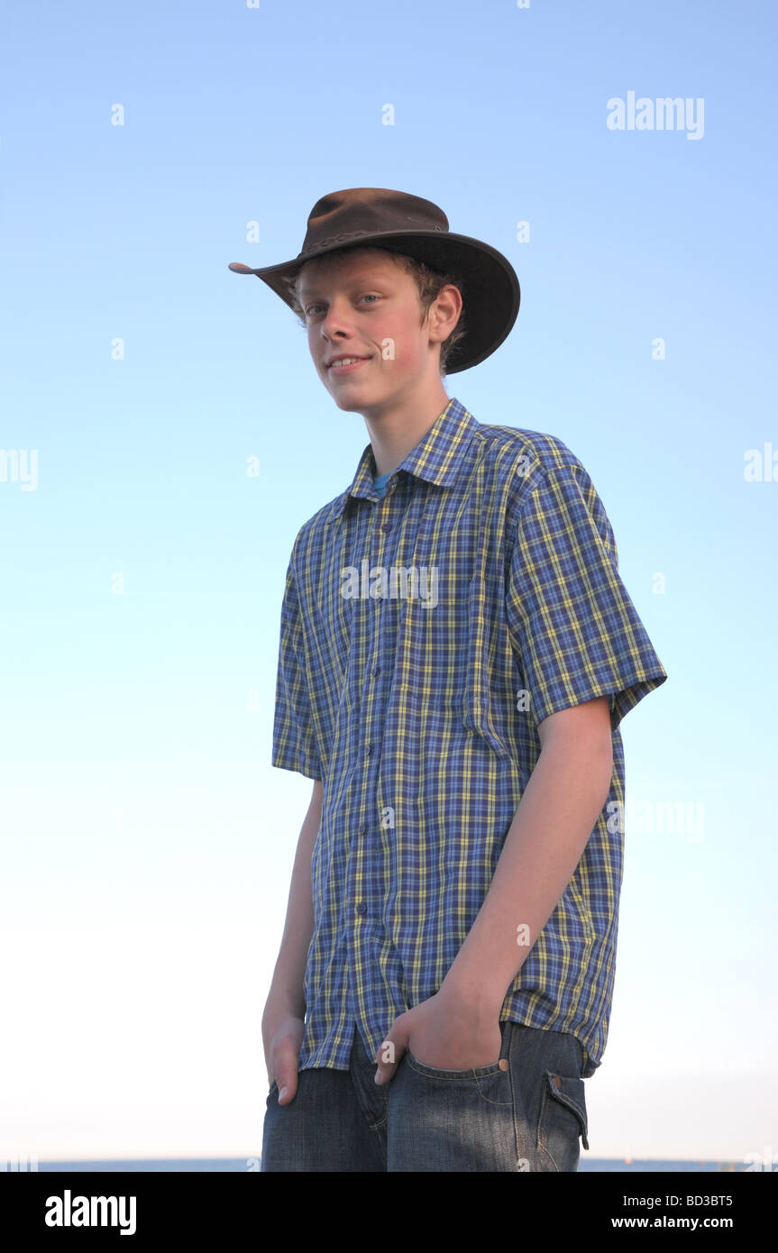 Smiling teenage boy wearing an Aussie hat on the beach one summer evening at sundown. Stock Photo