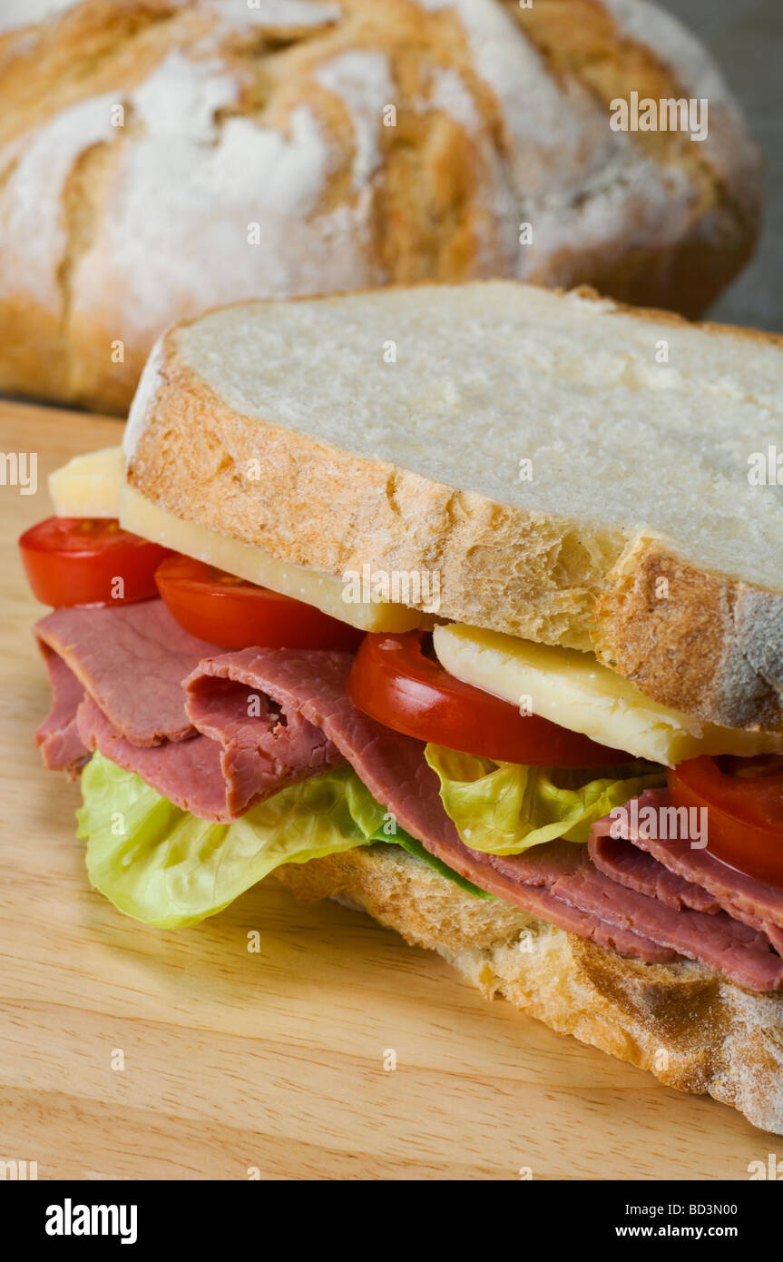 A sandwich of french boule white bread with a filling of lettuce pastrami cheddar cheese and