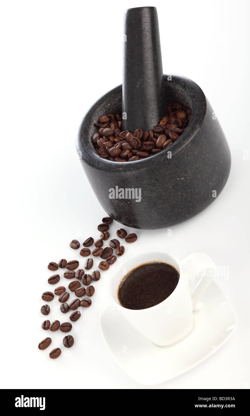 Coffee being ground with mortar and pestle, next to a cup of Espresso