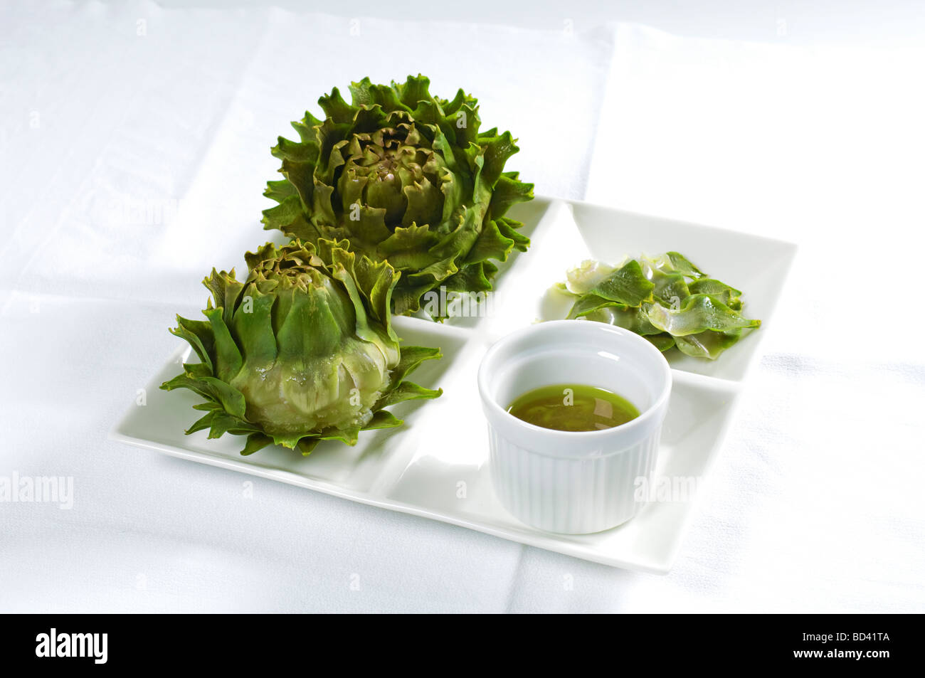 Cooked artichoke heads with vinaigrette Tear off a leaf dip the edible base in dressing and remove flesh with teeth Stock Photo