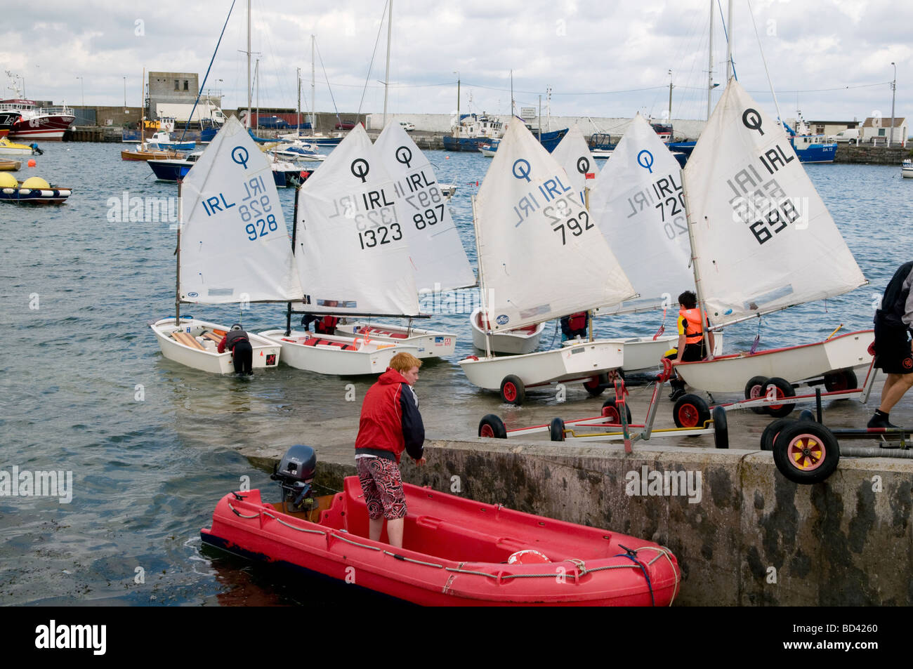 Children launching their Optimist sailing dinghies at the slipway in