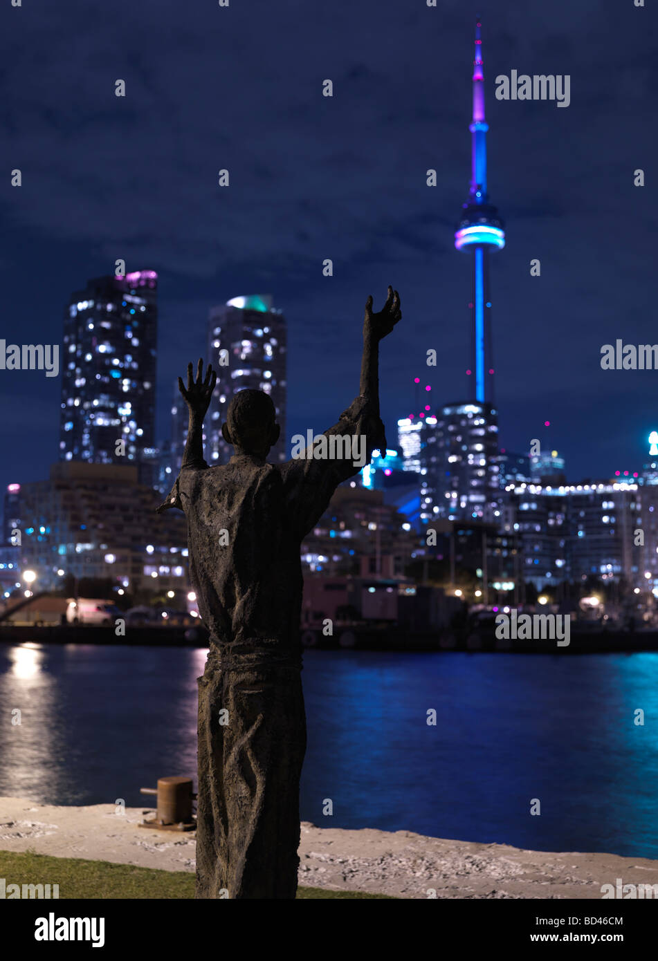 Sculpture of a man facing CN Tower with raised hands Stock Photo