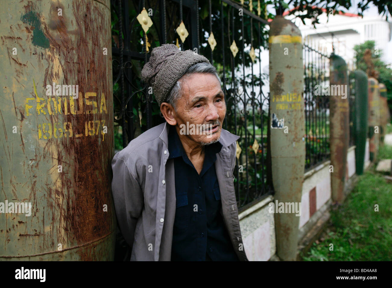 Phonsavan, Laos 2006 : A resident  with his fence made from US cluster bomb casings dropped on the area during the Vietnam War. Stock Photo