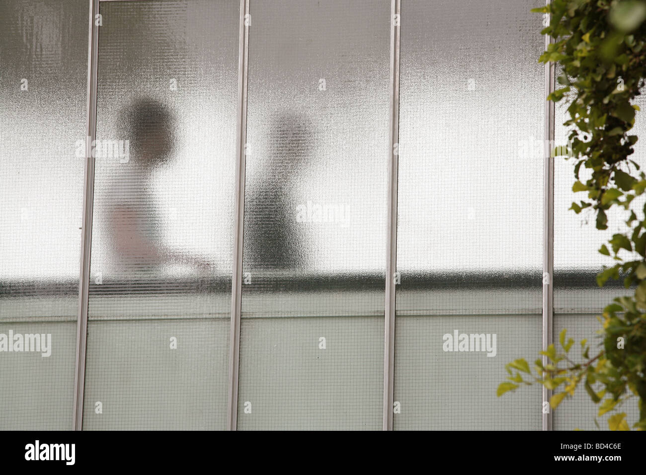 diffuse outlines of people walking behind glass Stock Photo
