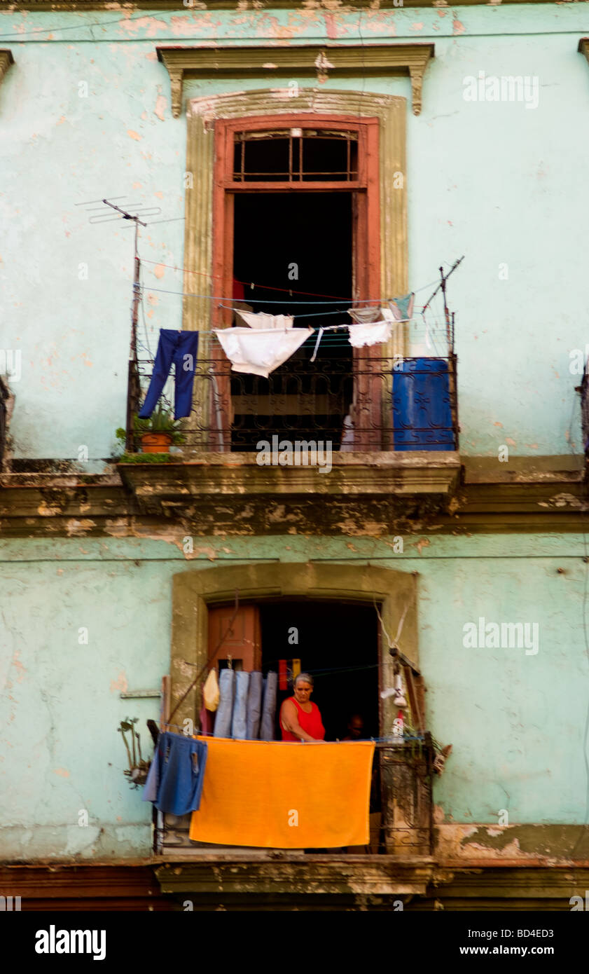 Havana Cuba Habana woman hanging laundry from porch in old worn and colorful apartment buildings in downtown city Stock Photo