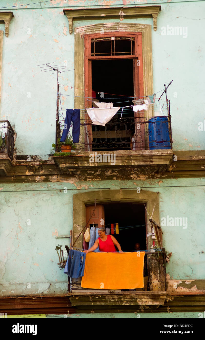 Havana Cuba Habana woman hanging laundry from porch in old worn and colorful apartment buildings in downtown city Stock Photo