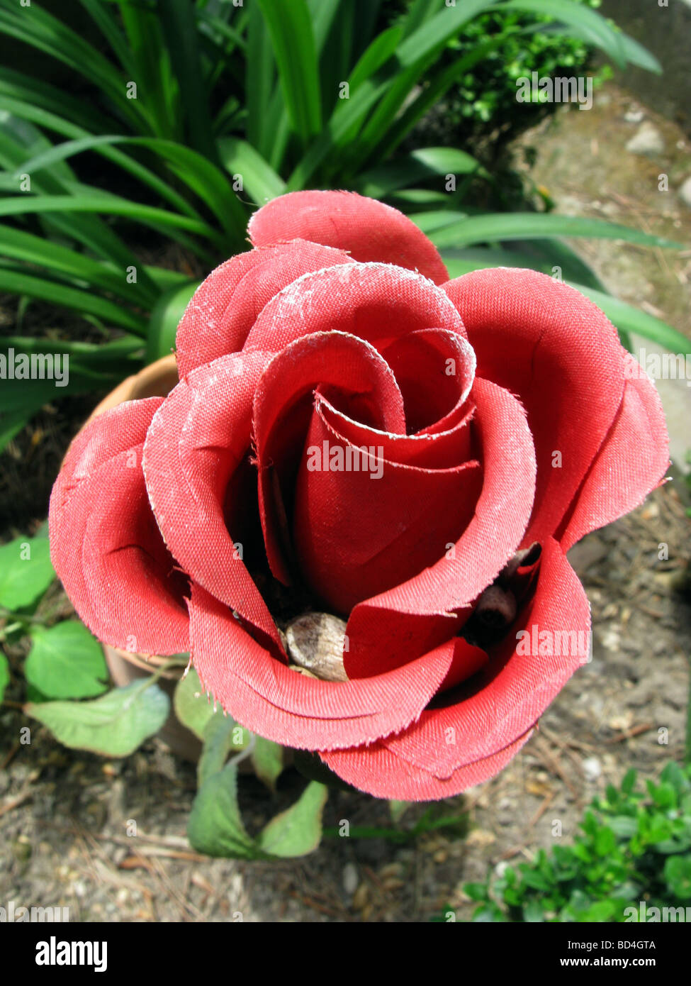 detail of red plastic artificial rose flower in garden Stock Photo - Alamy