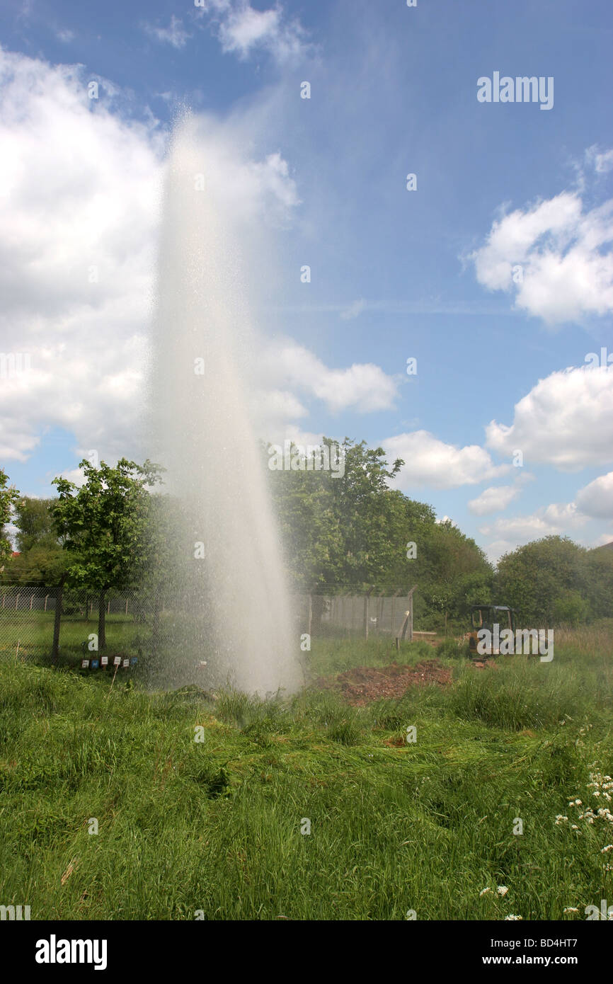 A burst watermain and an Enterprise Plc van on a sunny day in the UK Stock Photo