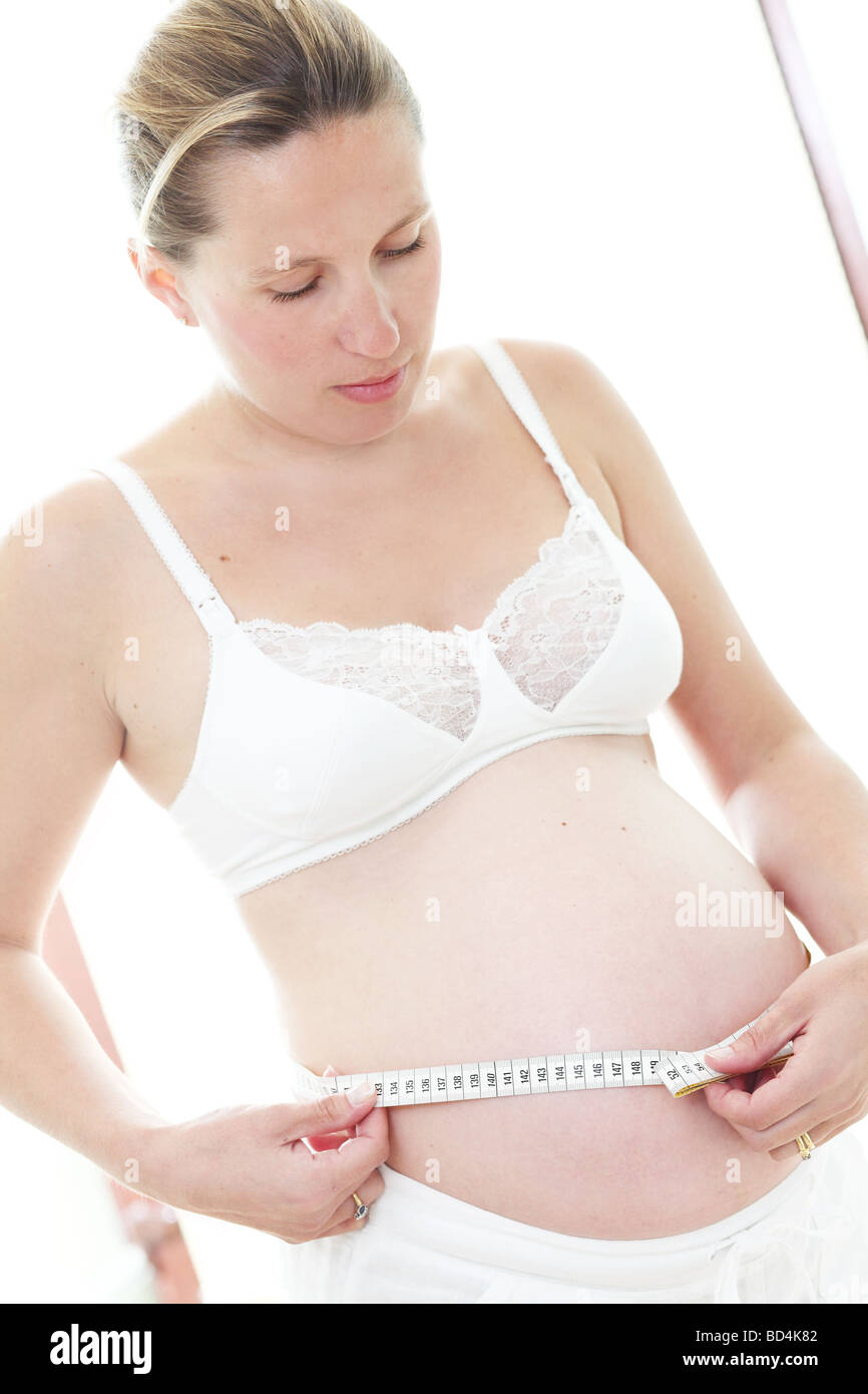 A pregnant woman measuring the size of her bump with a tape measure