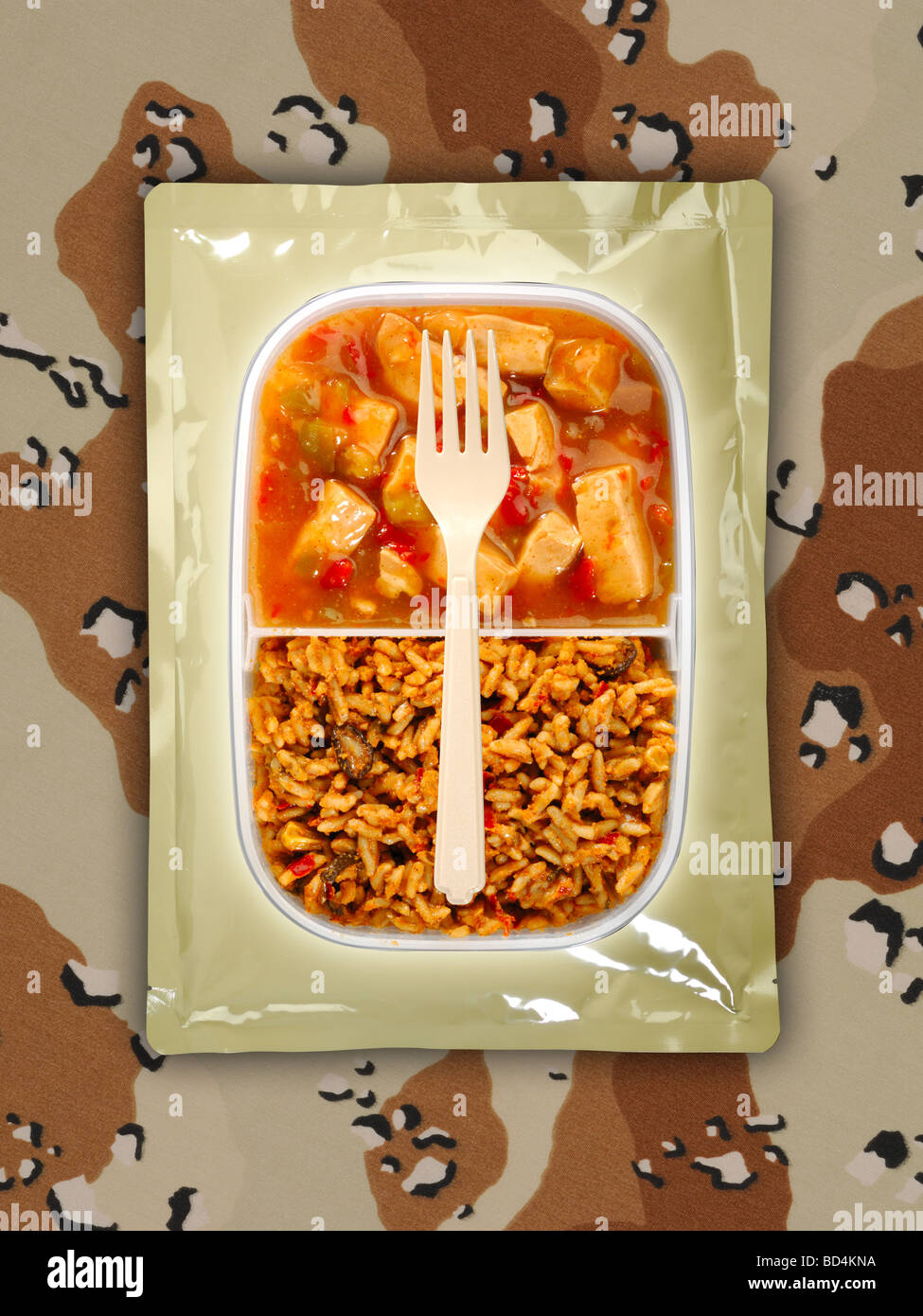 A military food ration package with a fork on a background of tan camouflage, spicy chicken with fried rice Stock Photo