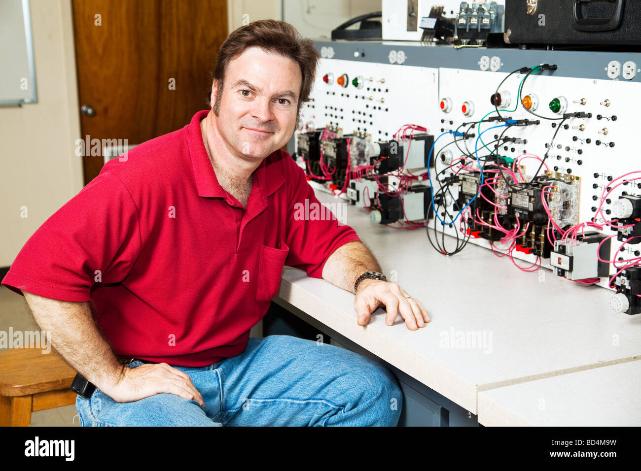 Electrical engineering teacher sitting at an industrial motor control