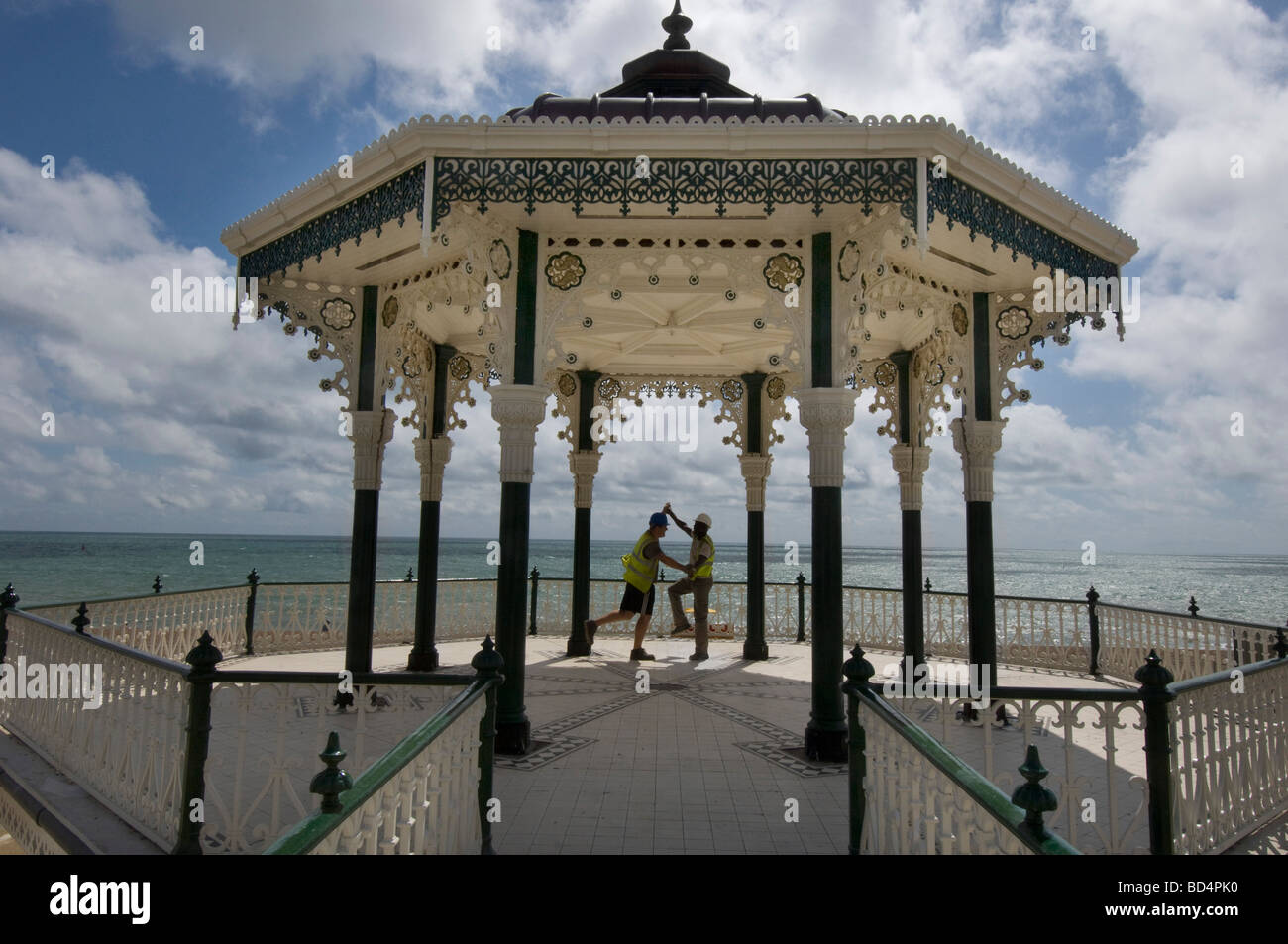 Two burly builders in hard hats and safety vests dance to celebrate the million pound refurbishment of Brighton bandstand. Stock Photo