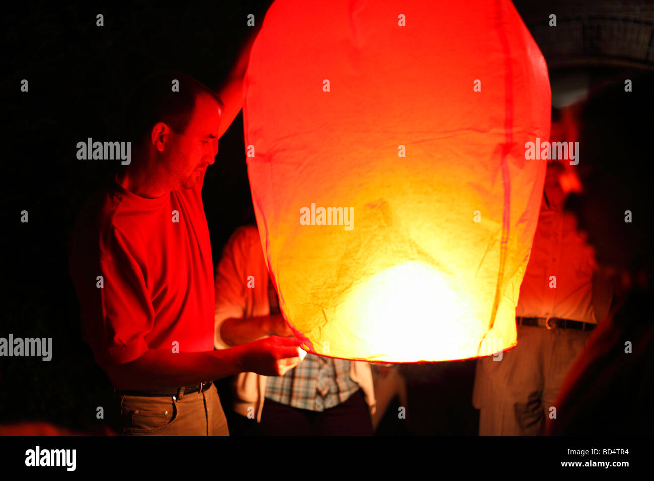 man launches sky lantern; floating lantern Stock Photo