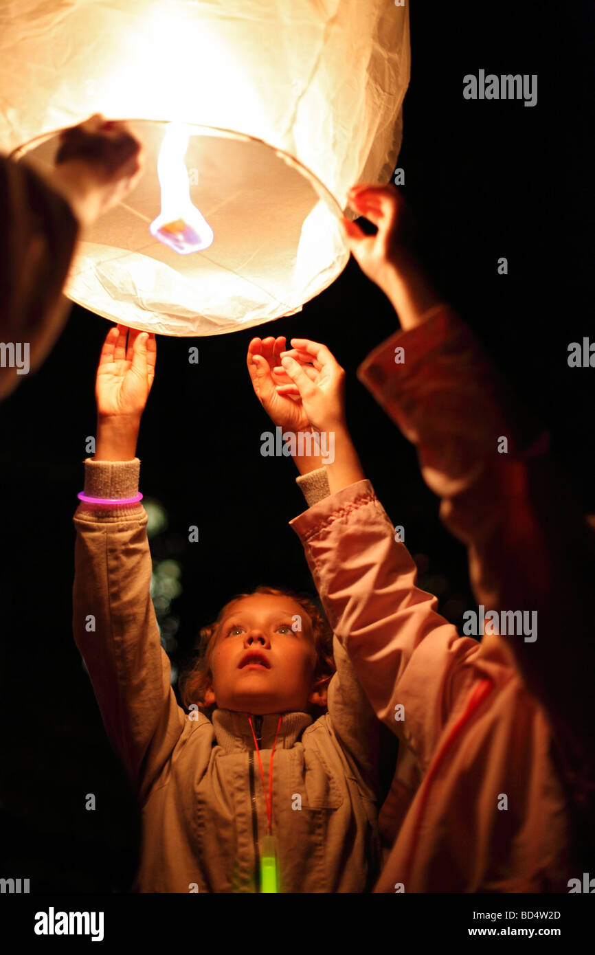 kids launch a sky lantern; Thai lantern; floating lantern; model release available for the girl in the center Stock Photo