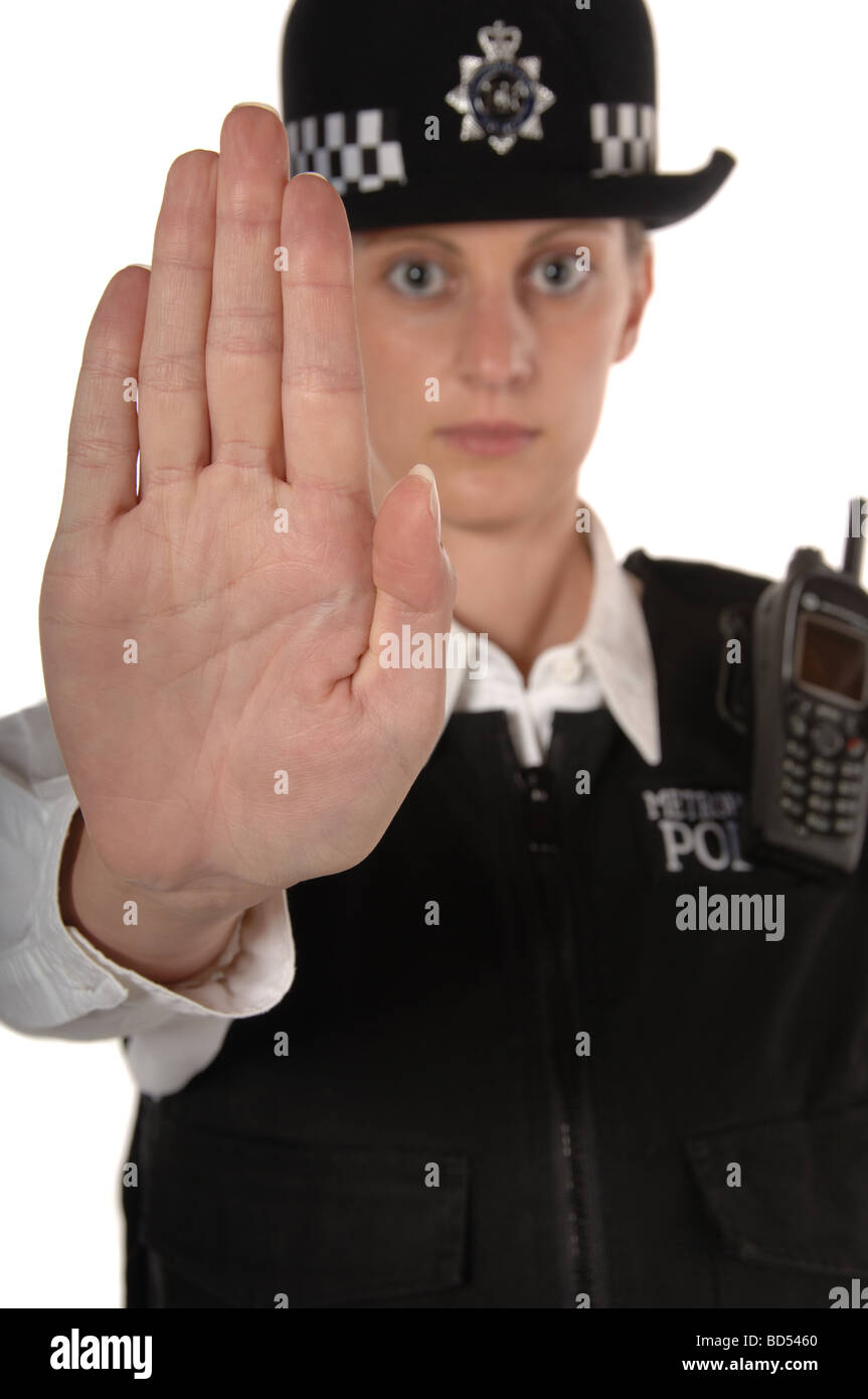 Uniformed UK female police officer with hand up showing stop isolated on white focus on hand Stock Photo