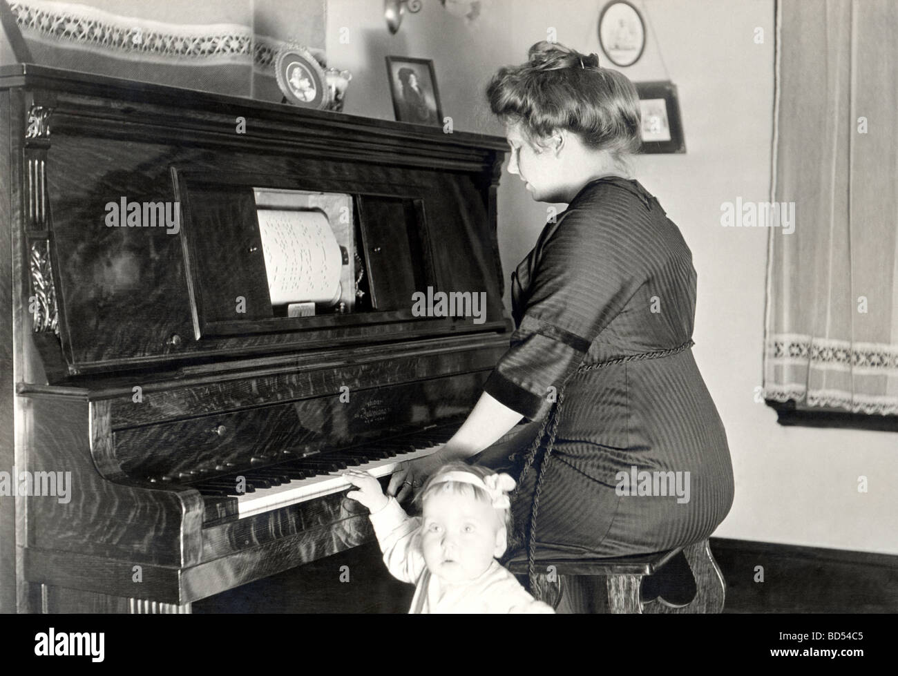 Mother at Player Piano with Daughter Stock Photo