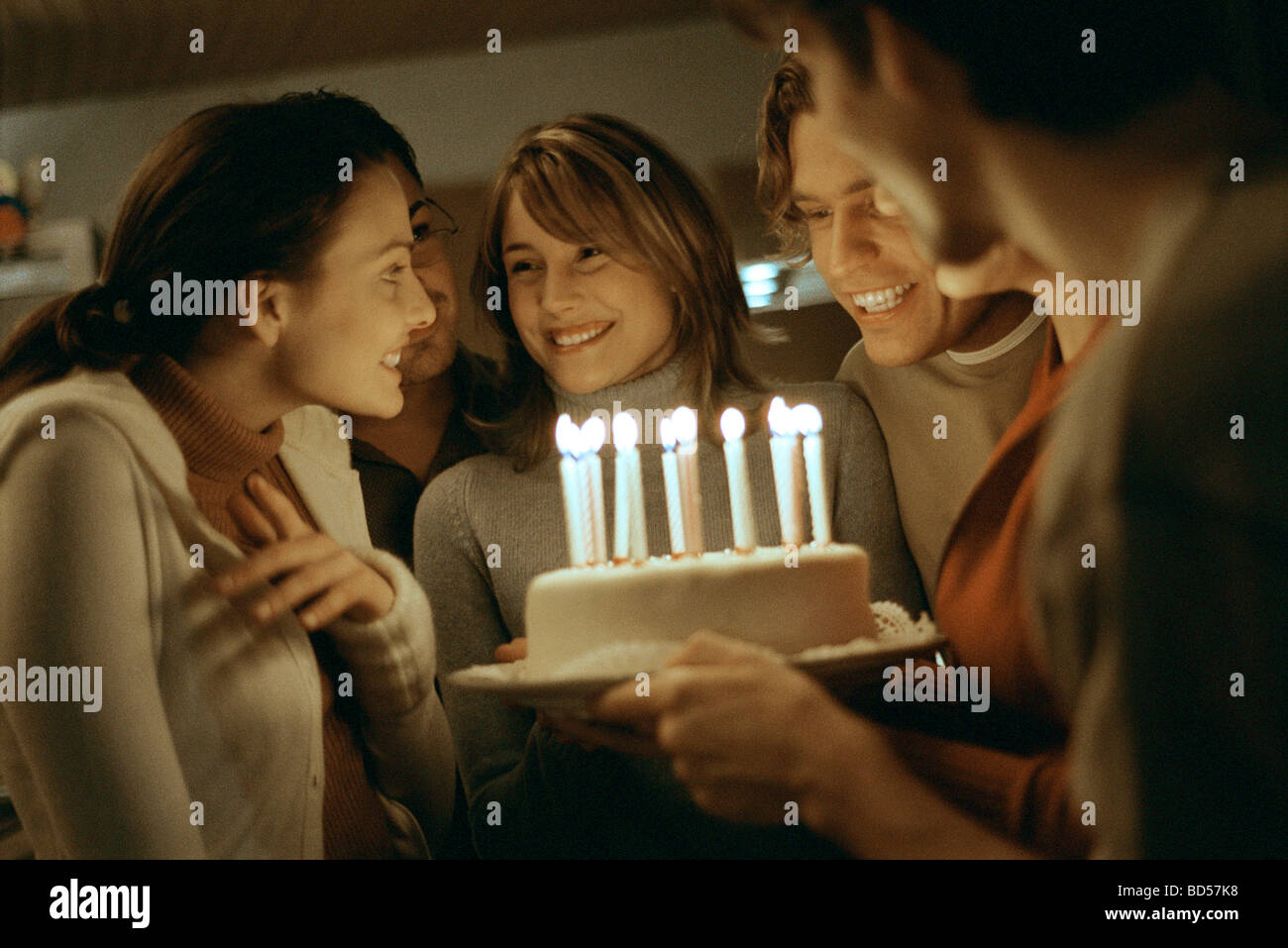 Birthday cake with lit candles being presented to young woman Stock Photo