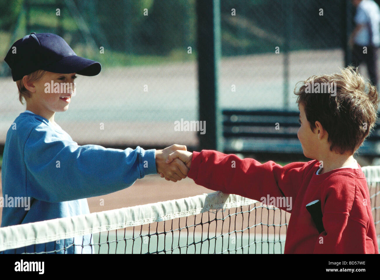 Girls shaking hands at net on tennis court Stock Photo