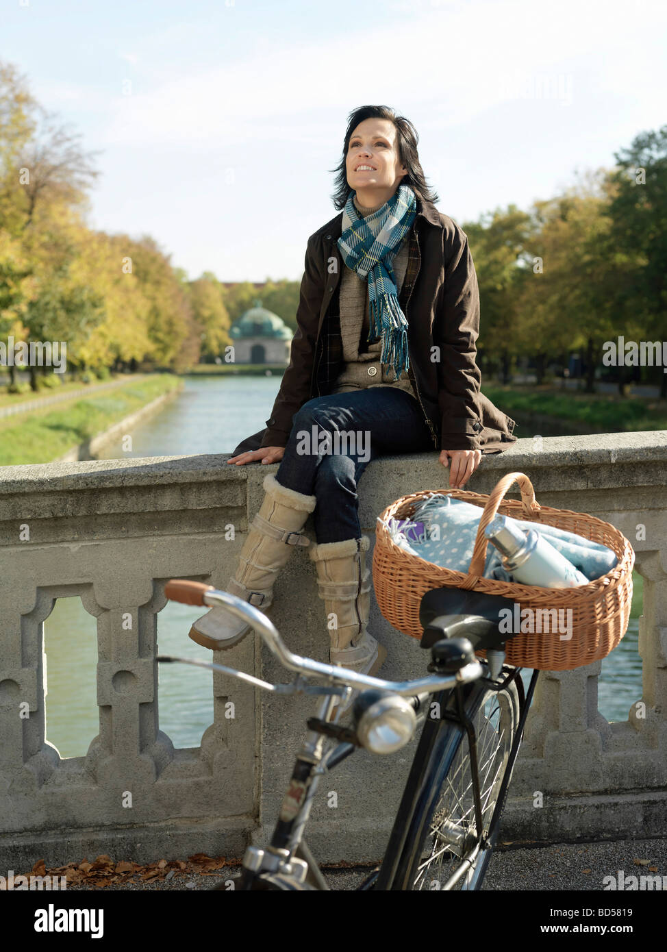 Woman sitting on river bridge in Autumn Stock Photo - Alamy