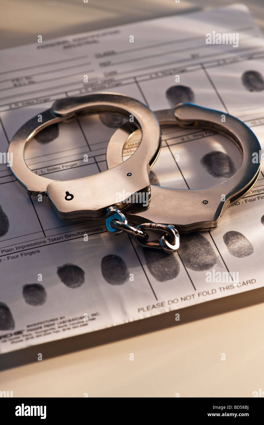 Hand cuffs on a page of fingerprints Stock Photo