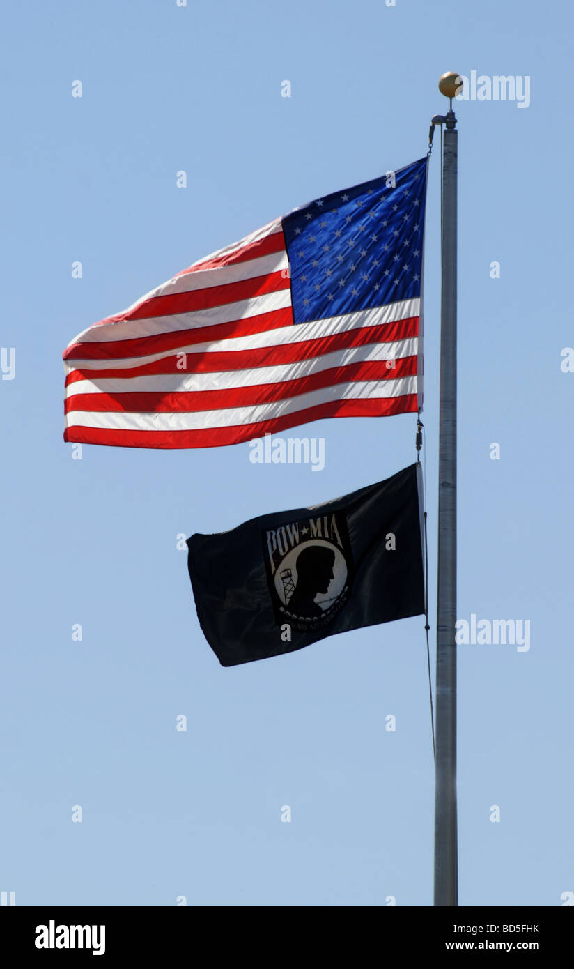 A POW-MIA flag flies below the American flag on a flag pole Stock Photo