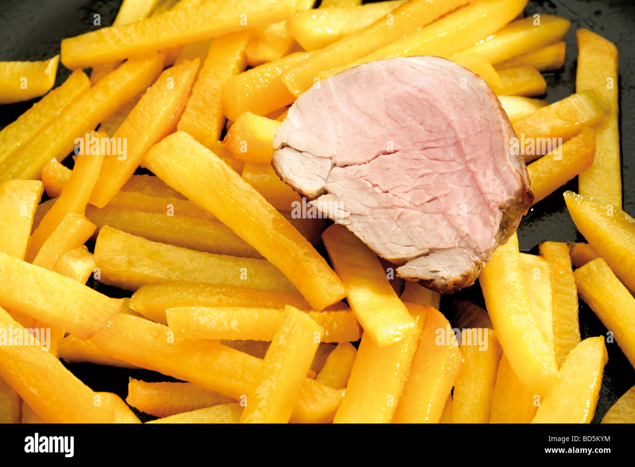 Turnip chips in a pan with a slice of pork fillet Stock Photo